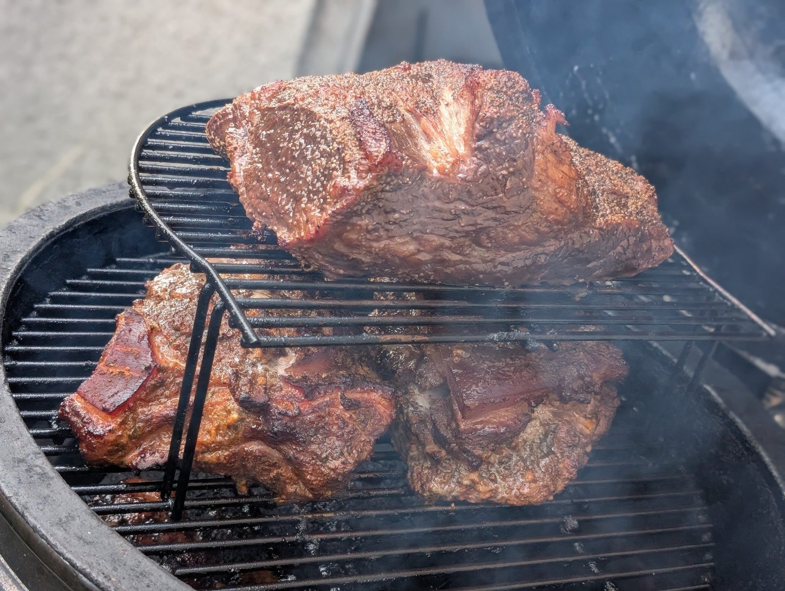 Meat stacked inside a smoker with smoke rising